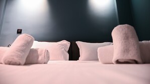 A hotel room with a bed, pillows, and rolled towels. - Cocoon Athenian Riviera by Neuvel (Vari-Voula-Vouliagmeni)