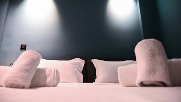 Una camera d'albergo con un letto, cuscini e asciugamani arrotolati.