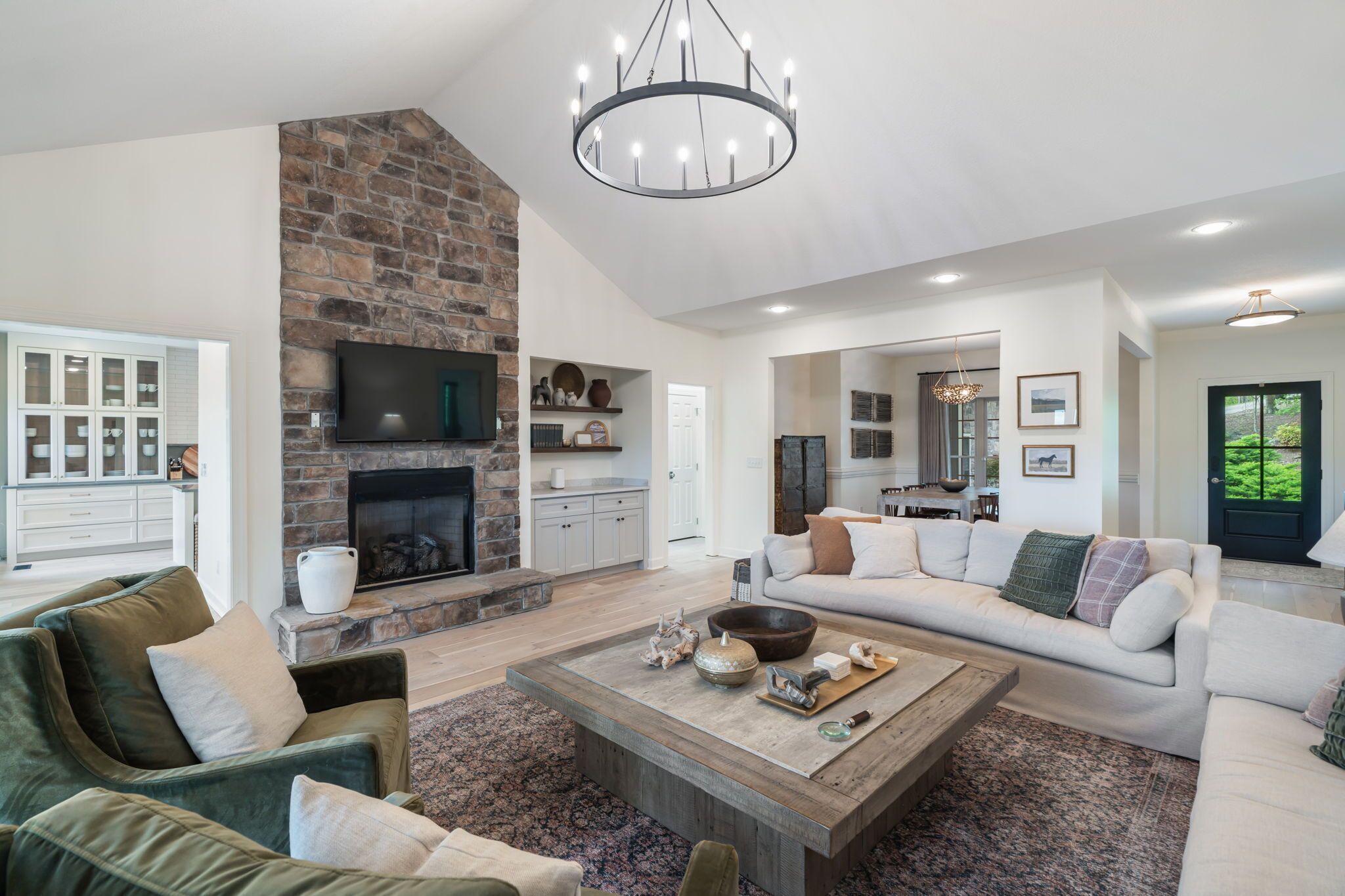 A spacious living room with a stone fireplace, a large sofa, a coffee table, and a television.
