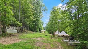Un terrain de camping avec des tentes, un espace pique-nique couvert et une terrasse en bois.