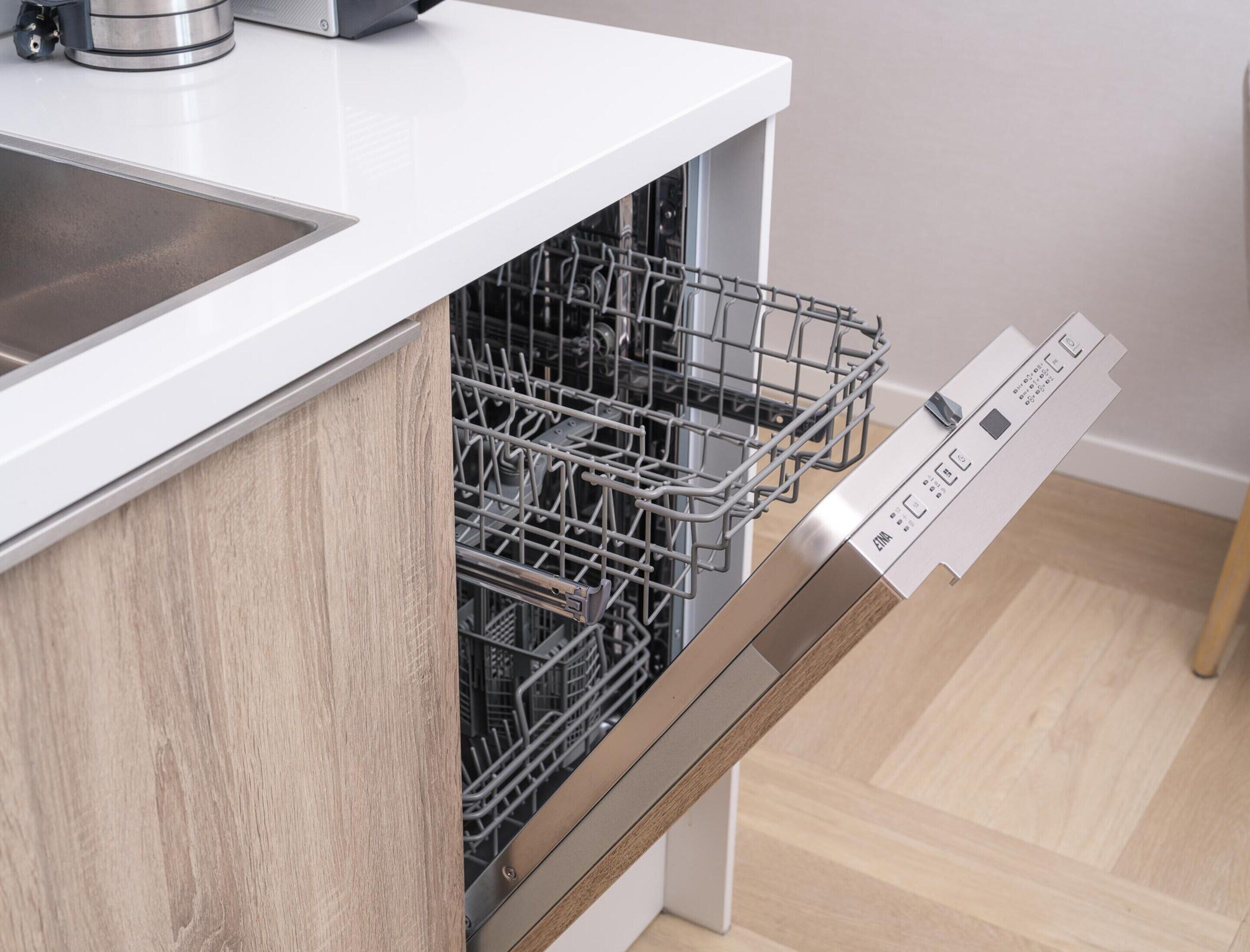 A modern kitchen with a dishwasher, a sink, and a wooden cabinet.