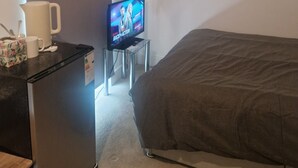 A hotel room with a bed, a small table with a television, a refrigerator, and a window with curtains. - Two rooms in a very quiet and clean environment. Central to getting services (Southampton)