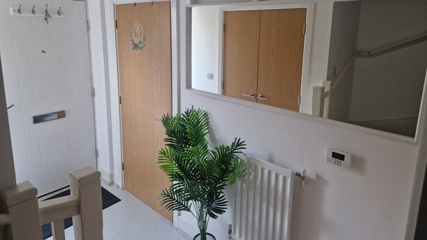 A hallway with a wooden door, a mirror, a radiator, and a potted plant. - Two rooms in a very quiet and clean environment. Central to getting services (Southampton)