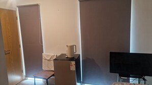 A room with a bed, a television, a small table with a kettle, a chair, and a window with blinds. - Two rooms in a very quiet and clean environment. Central to getting services (Southampton)