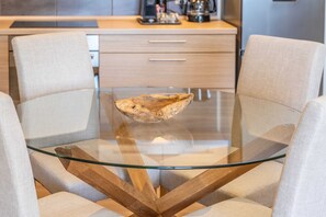 Ein moderner Essbereich mit einem Glastisch, zwei gepolsterten Stühlen und einem Holztisch.