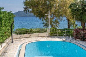 Ein Pool mit Blick auf Meer und Hügel.