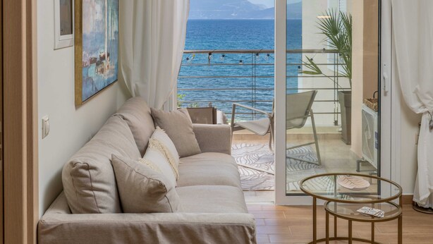 Een woonkamer met een bank, een glazen tafel en uitzicht op zee.