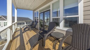 Eine überdachte Terrasse im Freien mit Rattanmöbeln und großen Fenstern.