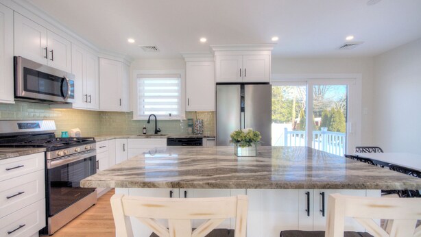 A kitchen with white cabinets, stainless steel appliances, a marble countertop, and a view to the outside. - VillaDaWhale Spacious 4bedroom game room house Somers Point bay near Ocean City (Somers Point)