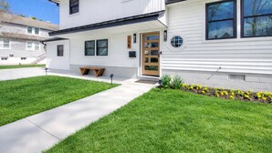 A two-story house with a front porch, a mailbox, and a small garden with yellow flowers. - VillaDaWhale Spacious 4bedroom game room house Somers Point bay near Ocean City (Somers Point)
