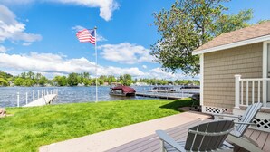 Une terrasse au bord du lac, avec un quai, un bateau et un petit chalet doté d’un espace salon extérieur.