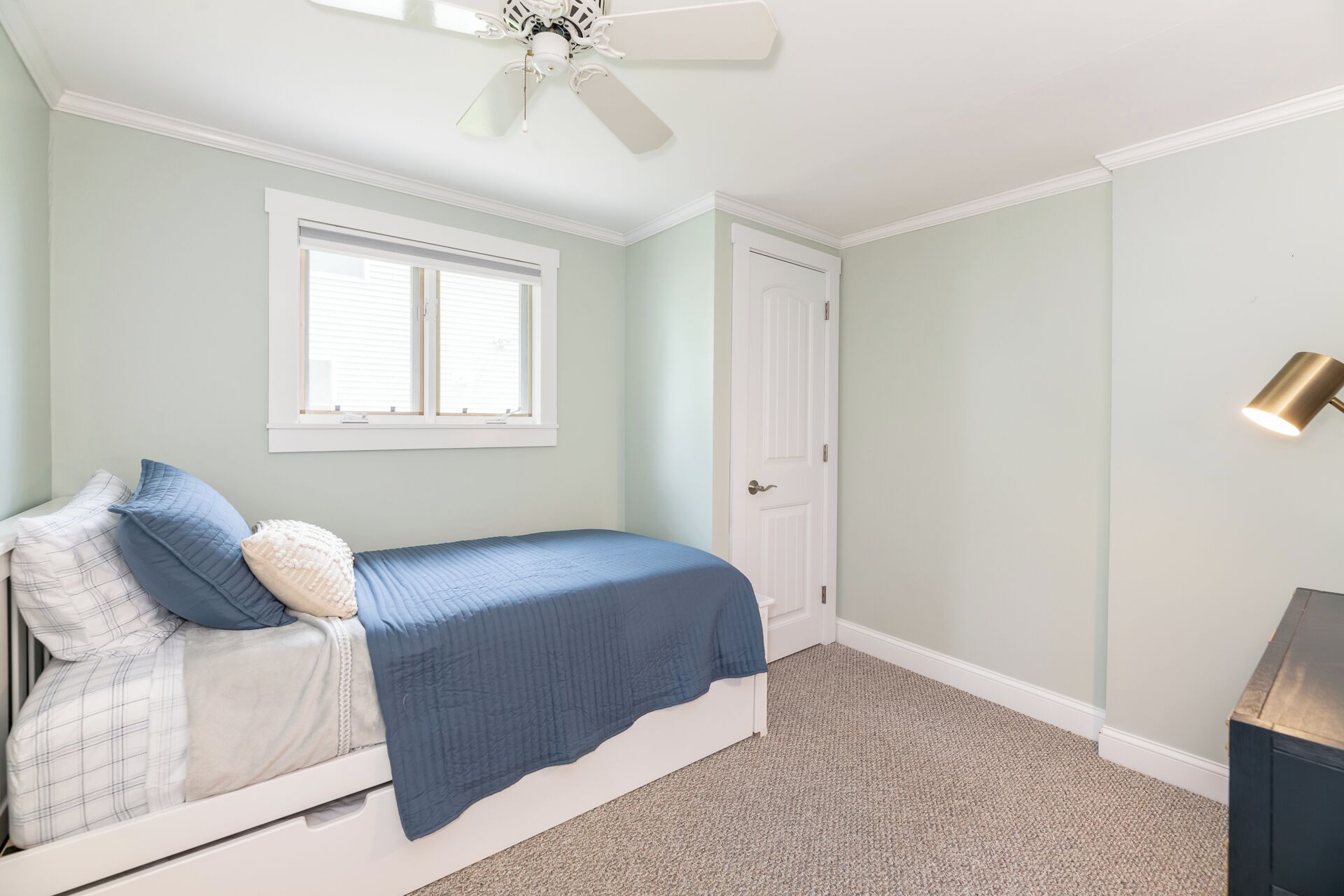 Une chambre à coucher avec un lit, une fenêtre, une porte, un ventilateur de plafond et une lampe.
