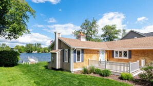 Une maison de plain-pied avec une fa çade en bois, une terrasse clôturée et une vue sur un lac.