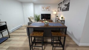 A dining area with a table, chairs, a TV, and a plant.