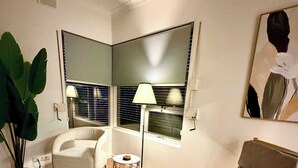 Una sala de estar con un sofá, un sillón, una lámpara de pie y una planta grande en maceta.
