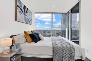 Une chambre moderne avec un grand lit, une vue sur la ville et un tableau accroché au mur.