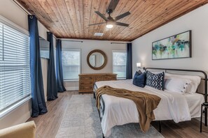 A bedroom with a bed, a ceiling fan, a dresser, a mirror, and a painting on the wall. - The Blue Bungalow on North-4 Mins to AT&T Stadium (Arlington)