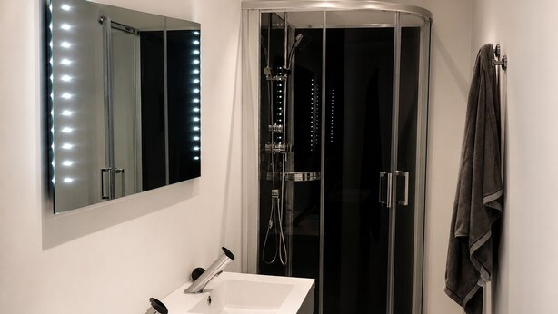 Ein modernes Badezimmer mit einem großen Spiegel, zwei Waschbecken, einer Duschkabine und einem Handtuchhalter.