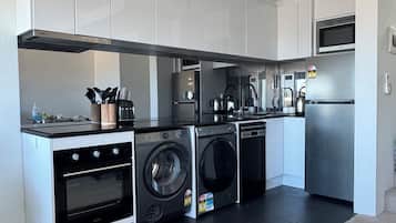Una cocina compacta con horno integrado, microondas y lavadora.