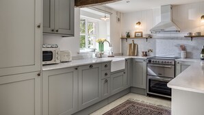 Una cocina con gabinetes grises, horno empotrado, microondas y una ventana con vistas a zonas verdes.