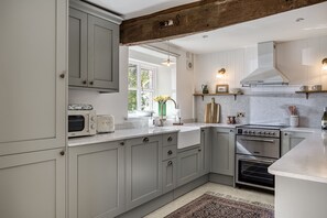 A kitchen with grey cabinets, a built-in oven, a microwave, and a window with a view of greenery. - Roundhill Farm Cottage sleeps 2 guests  in 1 bedroom (Naunton)