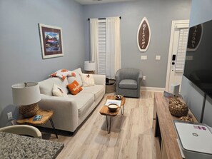 A living room with a sofa, armchair, coffee table, and a flat-screen TV.