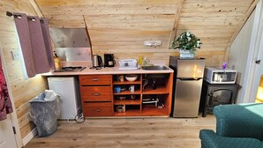 A compact kitchen with wooden cabinets, a refrigerator, a microwave, and a sink.