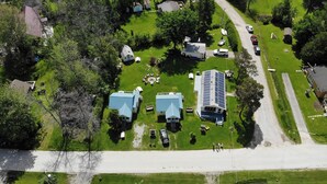 An aerial view of a residential area with multiple houses, a solar panel installation, and a road.
