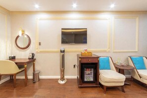 A room with a wooden table, a chair, a standing heater, a small refrigerator, and two sofas. - Queen T and T Dalat (Da Lat)