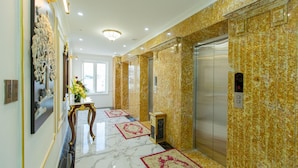A hallway with marble flooring, an elevator, and a wall-mounted decorative piece. - Queen T and T Dalat (Da Lat)