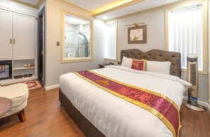 A hotel room with a large bed, a wardrobe, a mirror, a bedside table, and a standing heater. - Queen T and T Dalat (Da Lat)