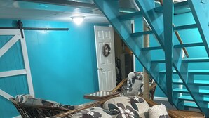 A wicker sofa with floral upholstery, a blue wall, and a staircase.
