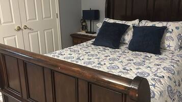 A bedroom with a wooden bed, a nightstand, a lamp, and a closed door.