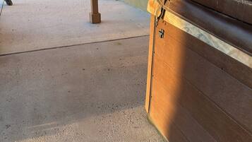 Une terrasse en béton avec un banc, une statue et un mur jaune sur lequel se projette une ombre.