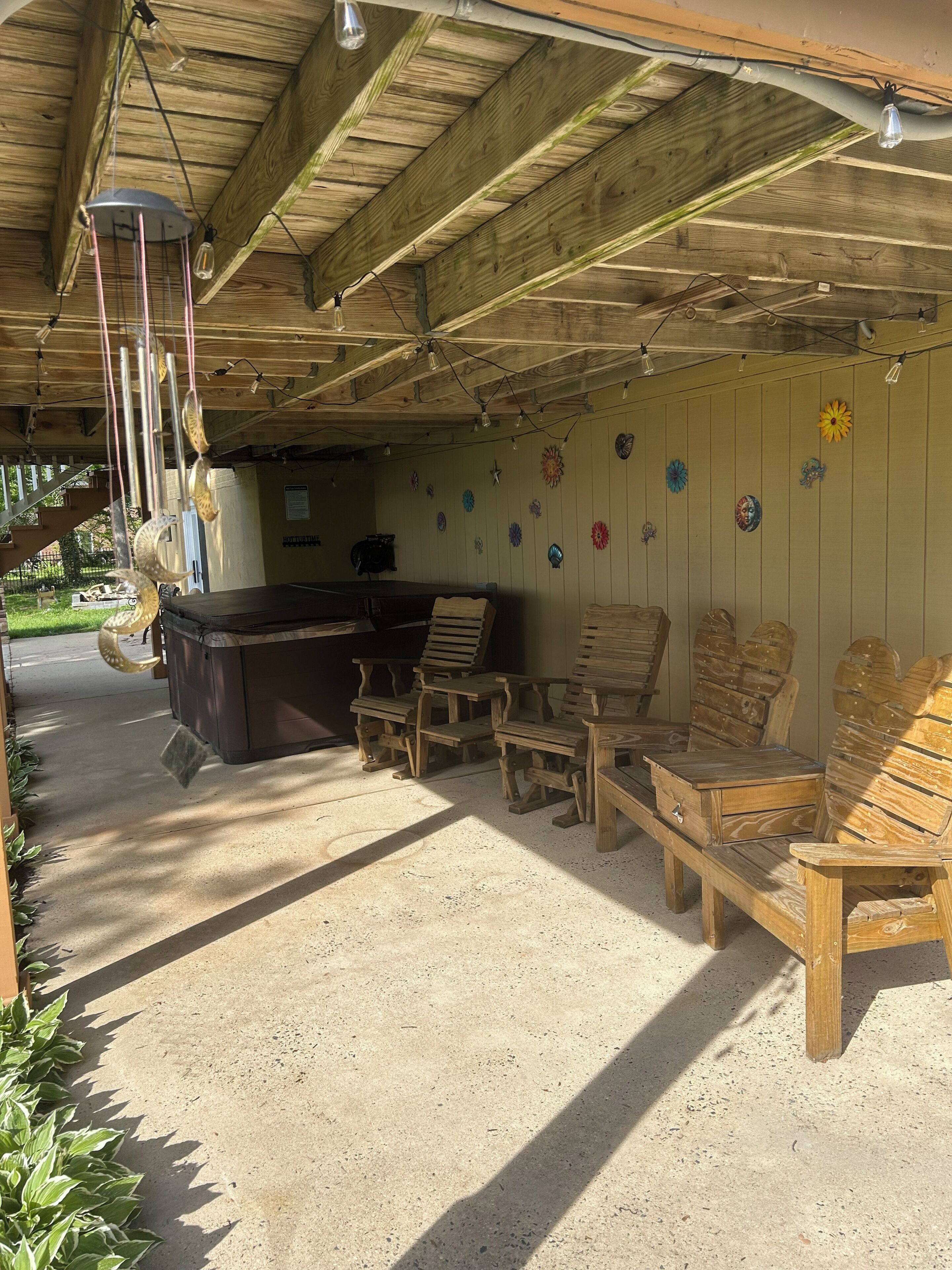 Een overdekt terras met houten meubels, een bar en decoratieve muurkunst.