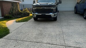 A driveway with a black pickup truck parked in front of a house with a garage.