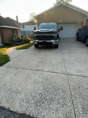 Eine Auffahrt mit einem schwarzen Pickup vor einem Haus mit Garage.