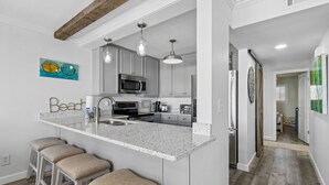 A kitchen with a central island, bar stools, a microwave, and a refrigerator.