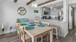 A dining area with a wooden table, chairs, and a kitchen in the background.