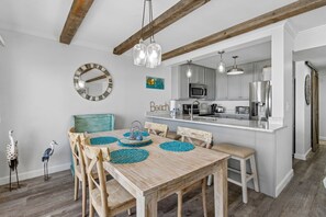 A dining area with a wooden table, chairs, and a kitchen in the background.