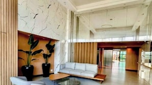 Un hall d’entrée spacieux, agrémenté d’un canapé moderne, d’une table basse et de plantes en pot.