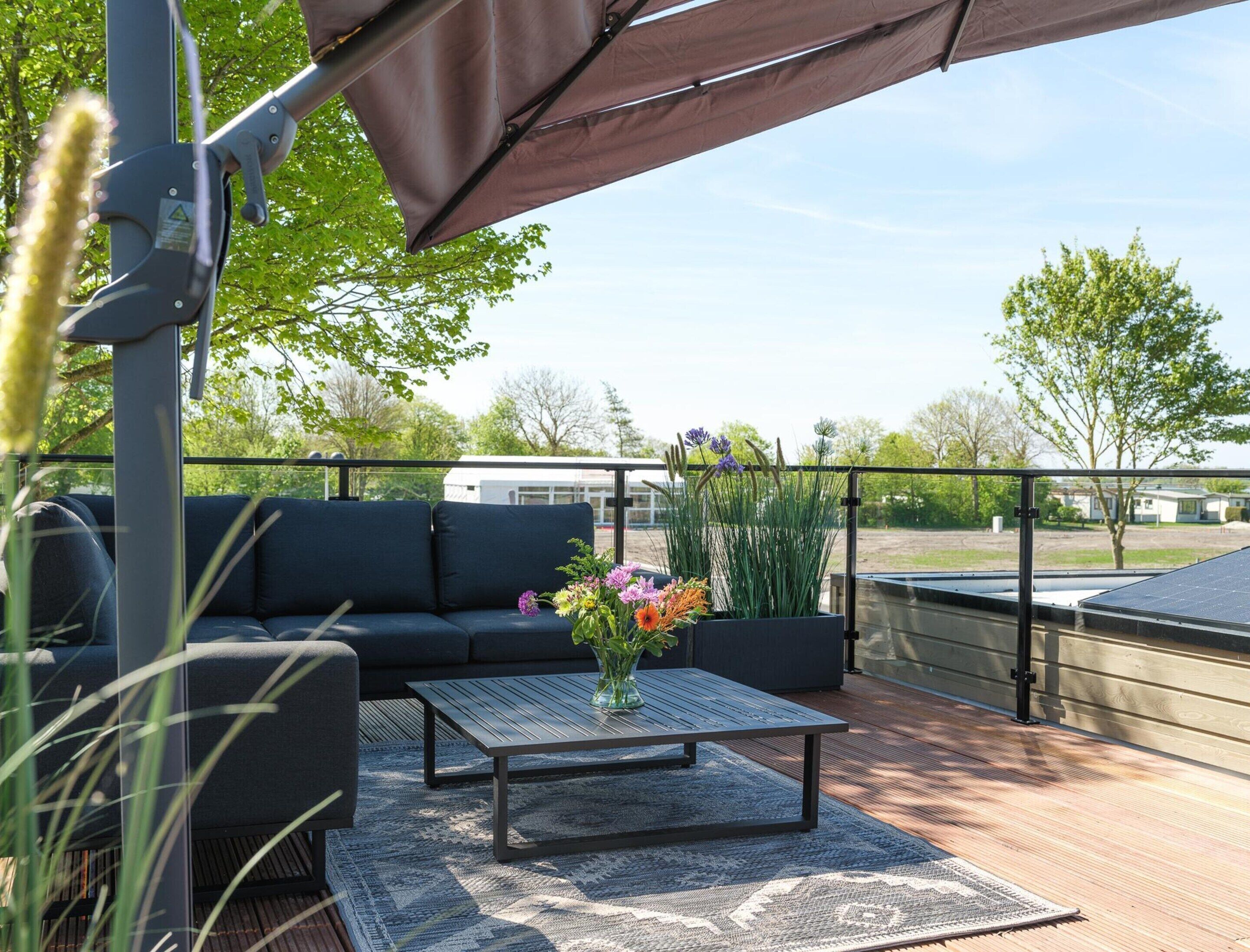 An outdoor patio with a sofa, a table, and a potted plant.