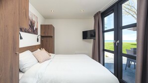Un dormitorio con cama, televisor montado en la pared y vistas al exterior.
