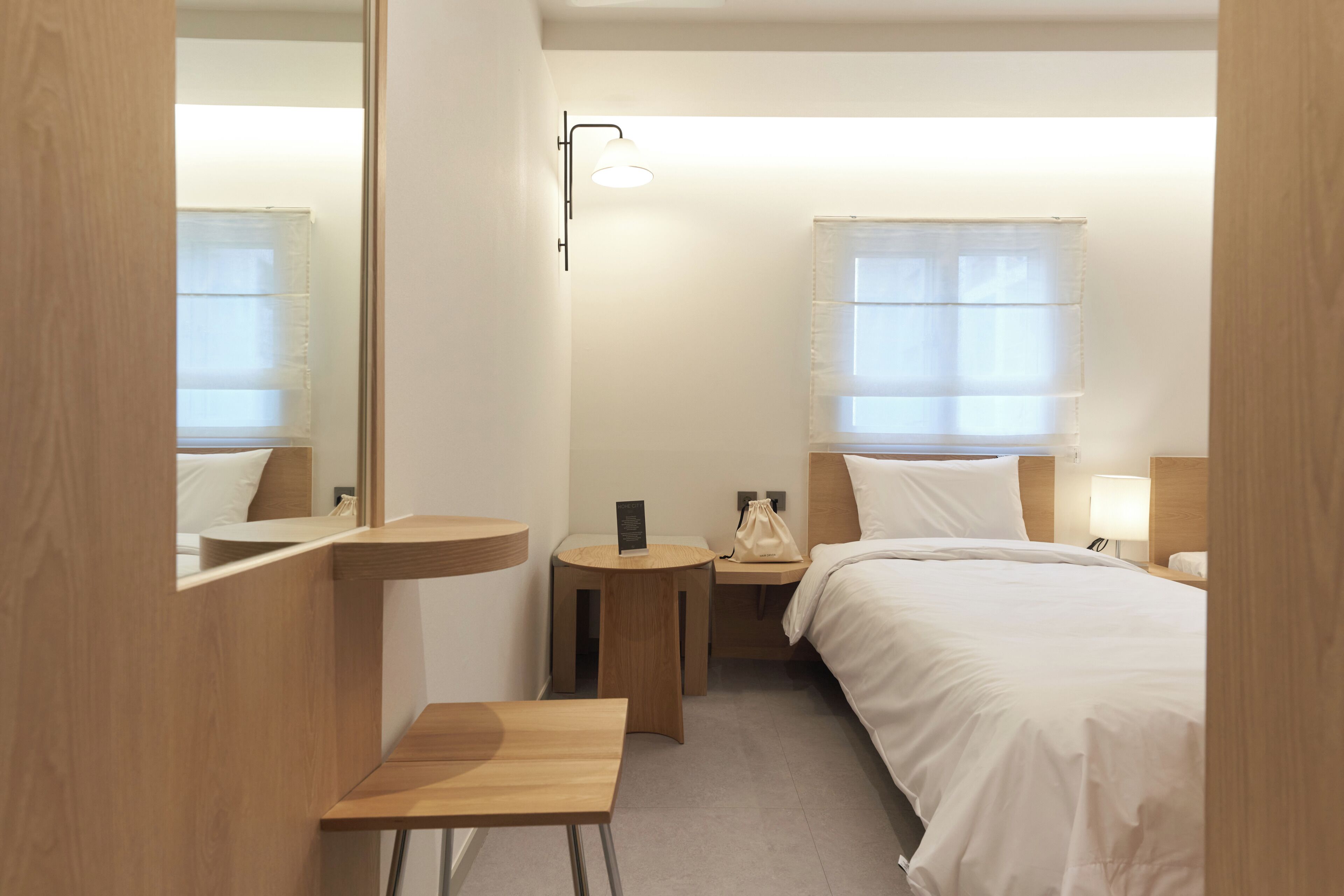 Une chambre d’hôtel avec un lit, une table de chevet, une lampe et un miroir.