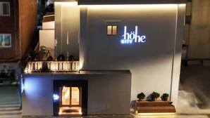 Un edificio moderno con un letrero que dice 'höhe CITY' y un pequeño espacio al aire libre con mesas.