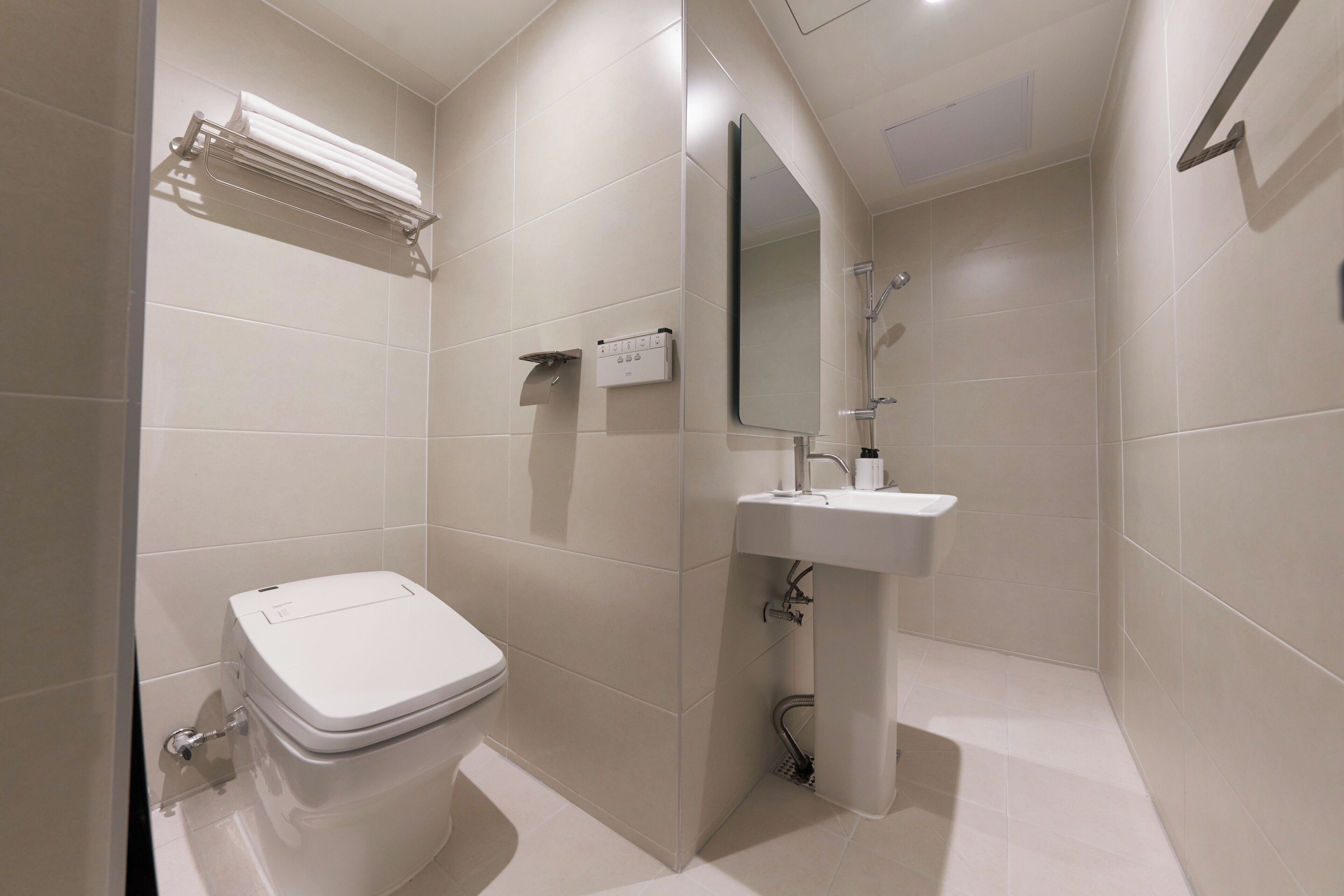 Un baño moderno con inodoro, lavabo y espejo.