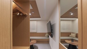 Una habitación moderna con un banco de madera, una mesa redonda y un televisor de pantalla plana montado en la pared.