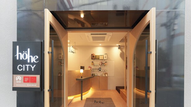Un interior moderno con un mostrador de recepción, una pequeña zona de estar y una exhibición de objetos en la pared.