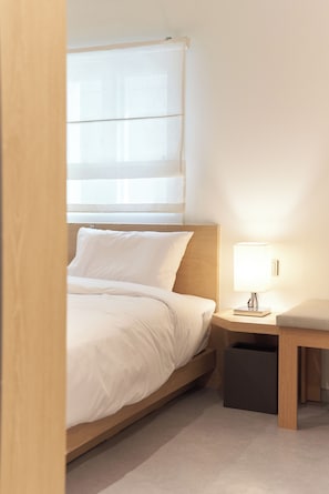 A hotel room with a bed, bedside table, lamp, and a window with blinds. - Hohe City Dongdaemun (Seoul)