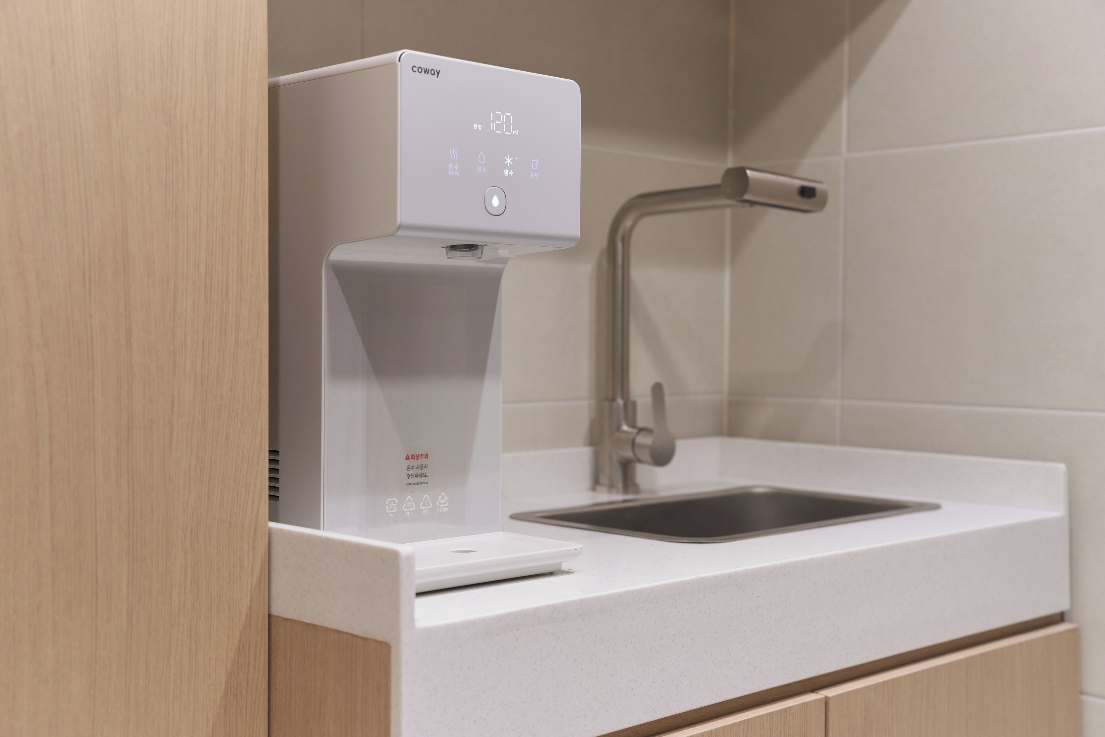 A modern kitchen with a built-in coffee machine, a sink, and wooden cabinets.